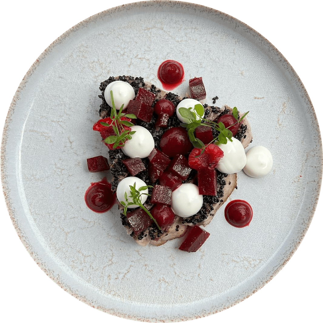 Betteraves vues du dessus sur une assiette blanche : dés et points de betterave, fromage frais, crumble noir, jeunes pousses.