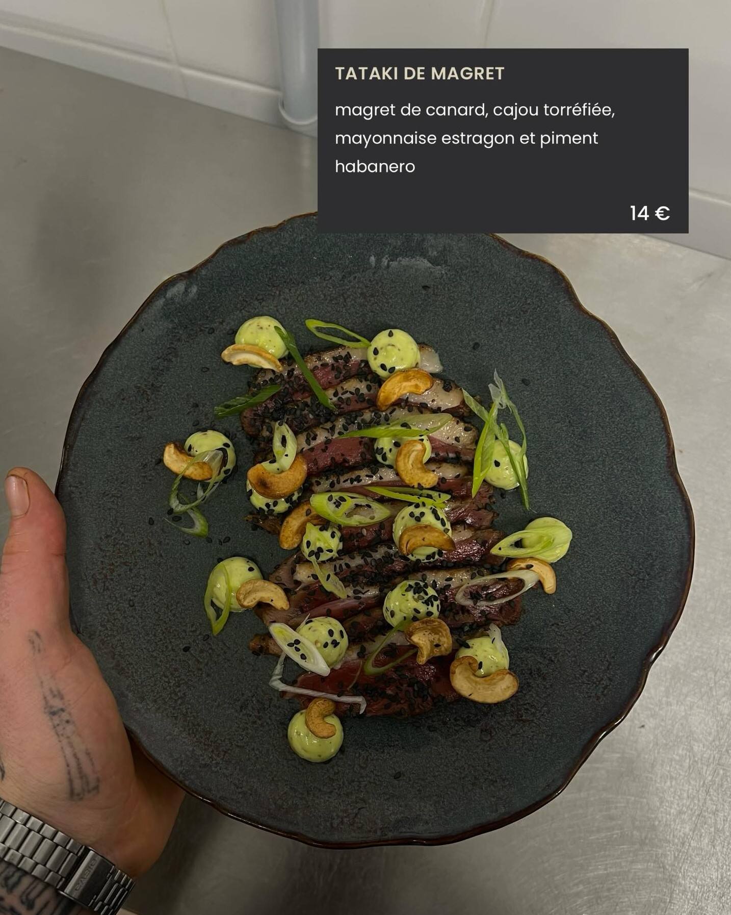 Tataki de magret tenu au-dessus du passe, avec l’intitulé de la carte incrusté : magret de canard, cajou torréfié, mayonnaise estragon et piment habanero.
