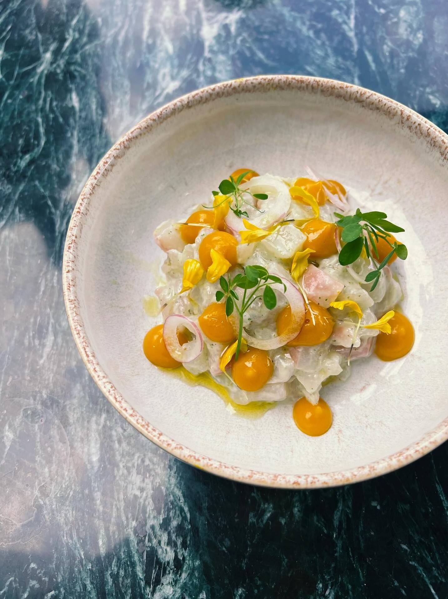 Crudo de poisson, points de gel orange, fleurs jaunes, marbre vert.