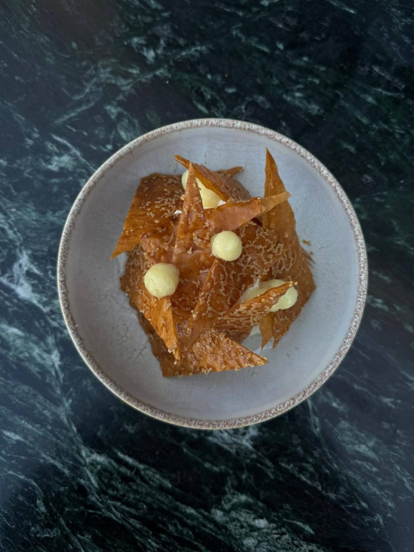 Mille-feuille yuzu vu du dessus, tuiles dorées et points de crémeux, marbre vert.