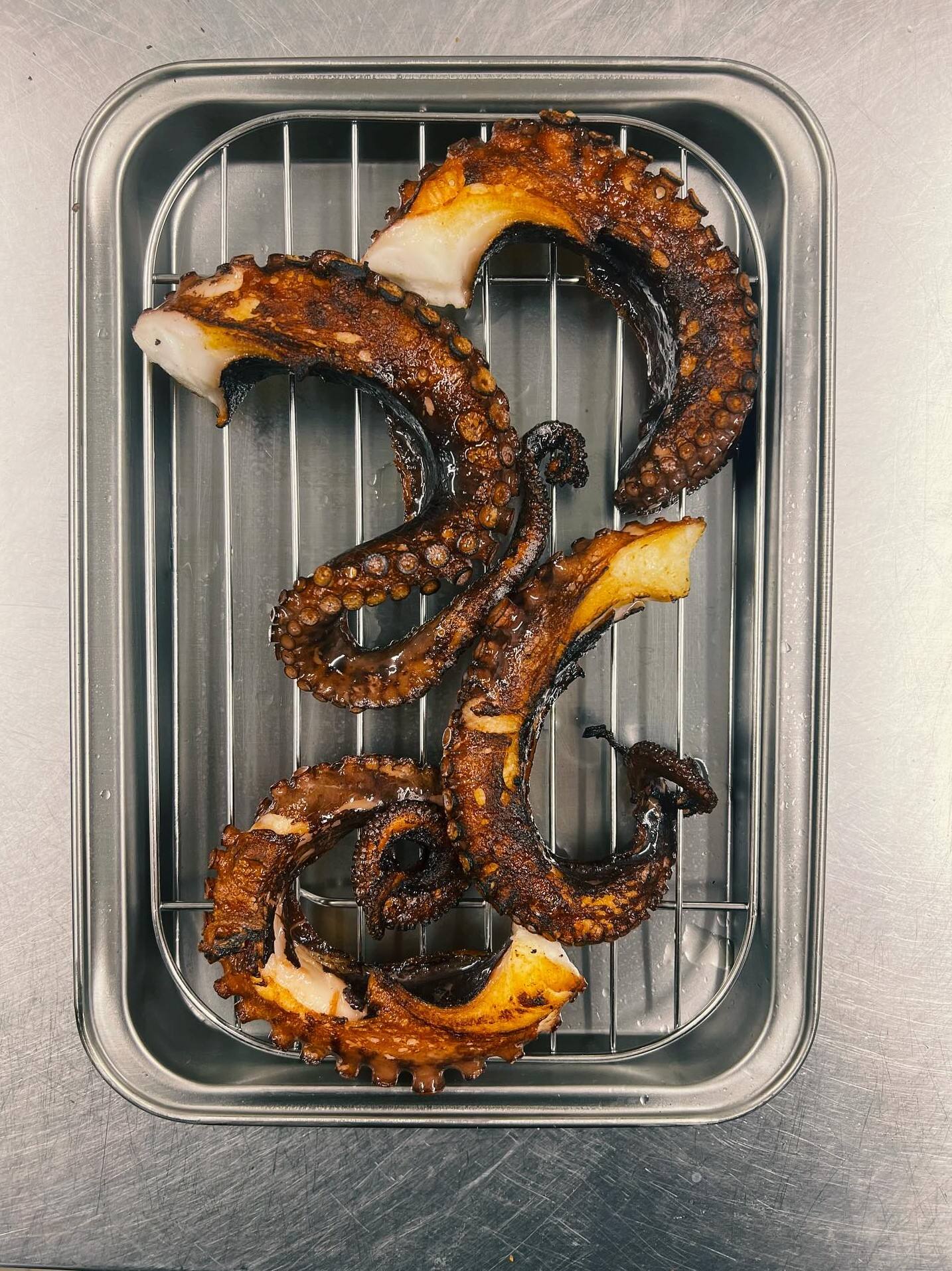 Tentacules de poulpe grillés sur une grille en inox.