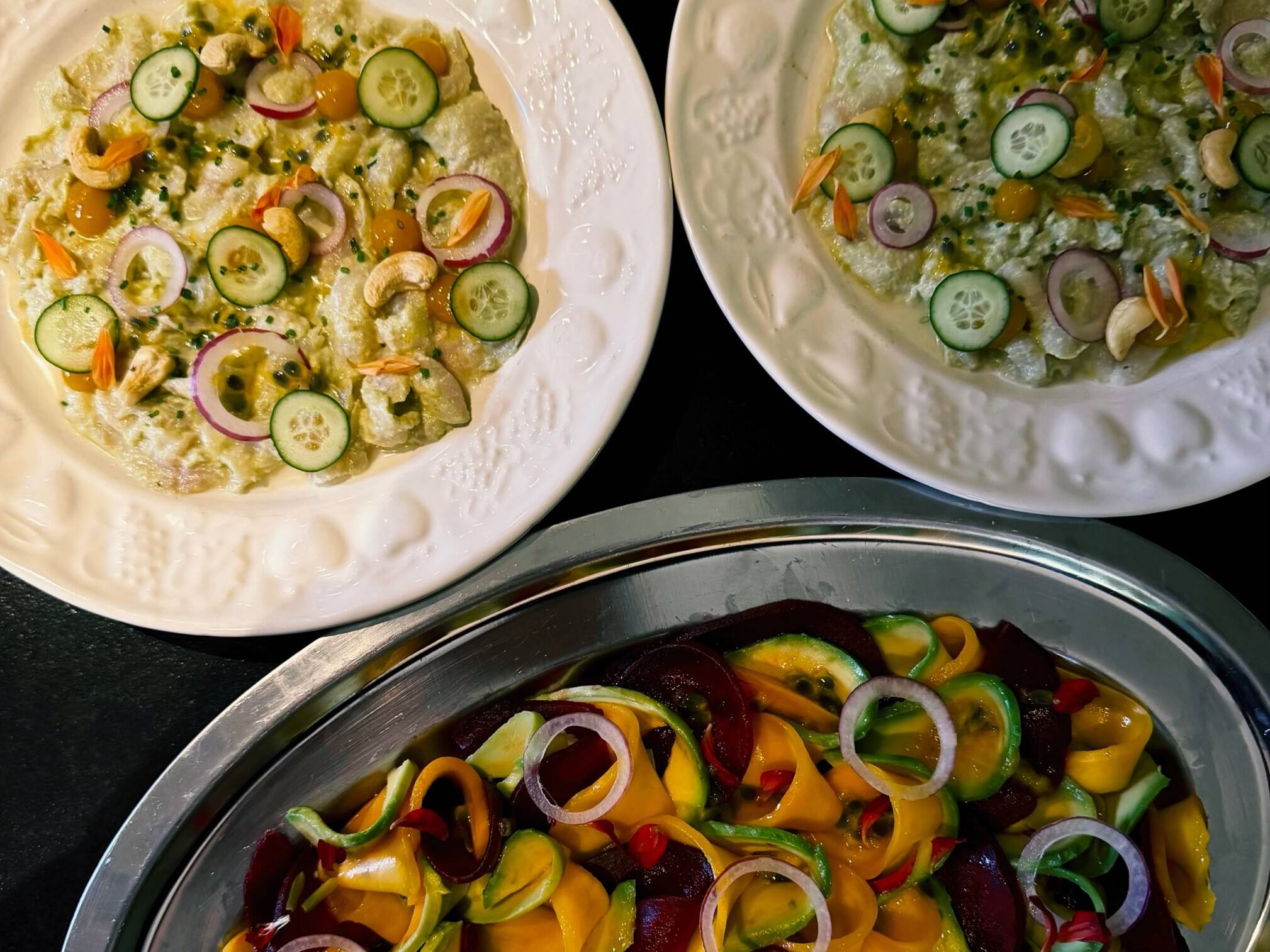Assiettes de légumes colorés posées au centre de la table, à partager.